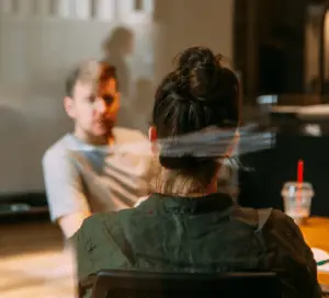 Image of two people talking through a window